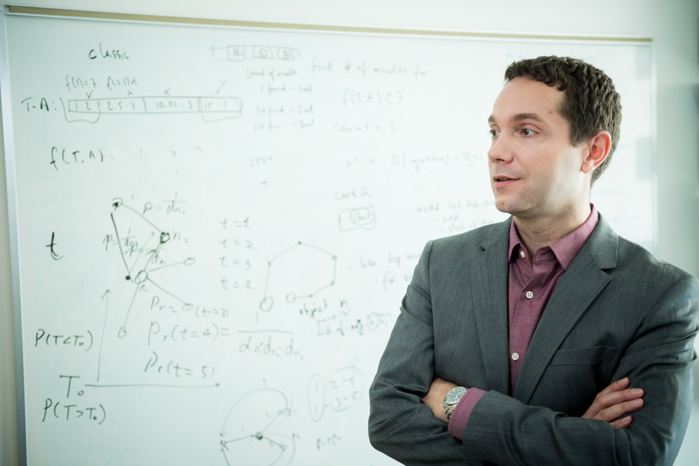 Mirek Riedewald in front of a whiteboard full of scribbles from a research discussion or office hours.
